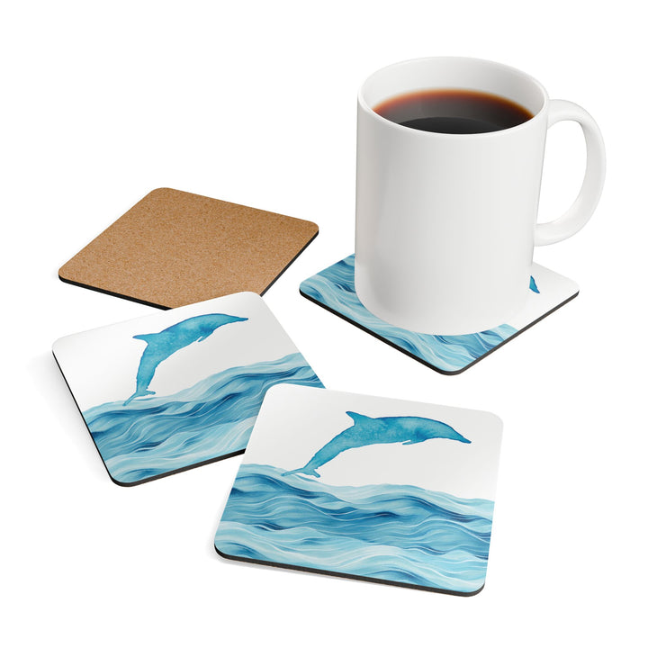 A lifestyle image of the dolphin coaster set in use, with a white coffee mug placed on one coaster and others arranged nearby, showing both the design and cork backing.