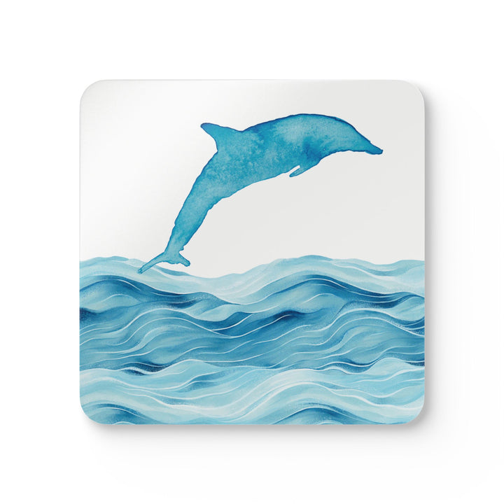 A square coaster featuring a watercolor-style dolphin leaping over ocean waves against a white background. The design is vibrant and detailed, creating a serene coastal look.